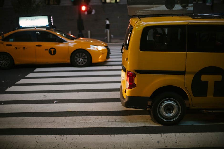 From above of contemporary shiny yellow cabs riding on asphalt roadway in New York at night