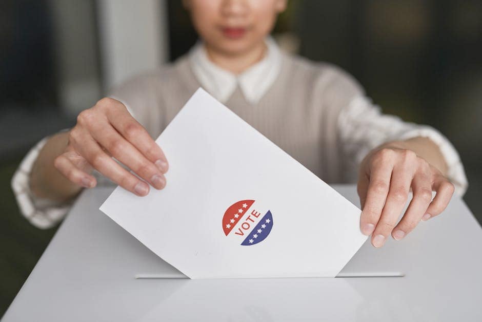 Close-up of hands holding a vote ballot, symbolizing election participation.