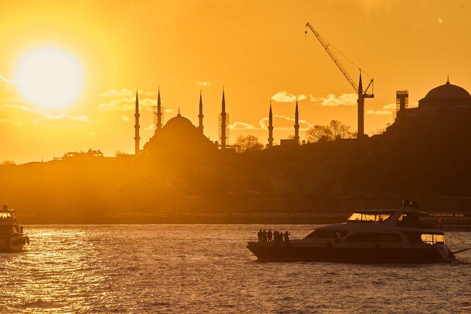 Silhouette of Istanbul mosques at sunset with vibrant golden hues and boats on the Bosphorus.