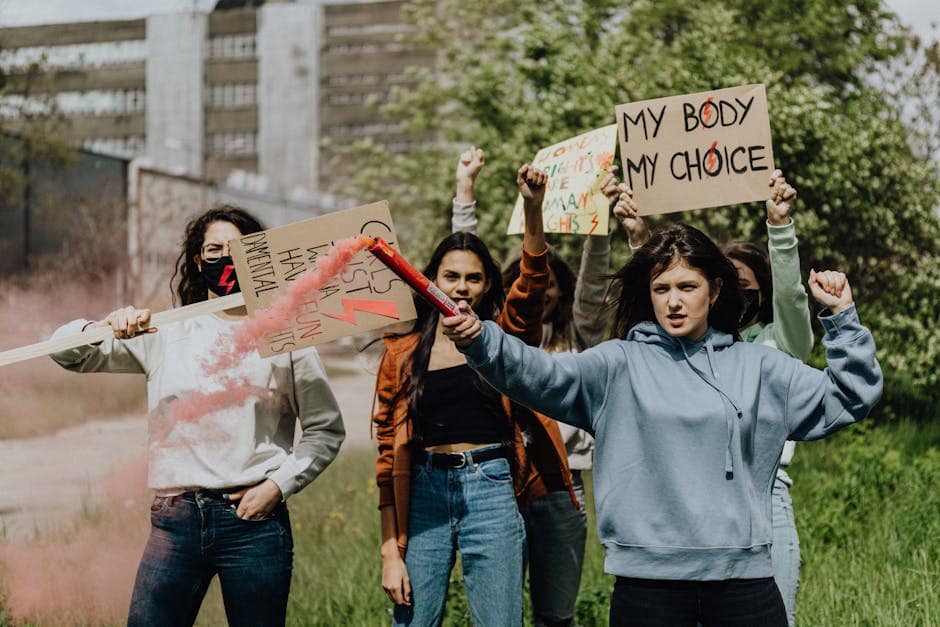 A group of women protesting with placards and smoke flares for human rights outdoors.