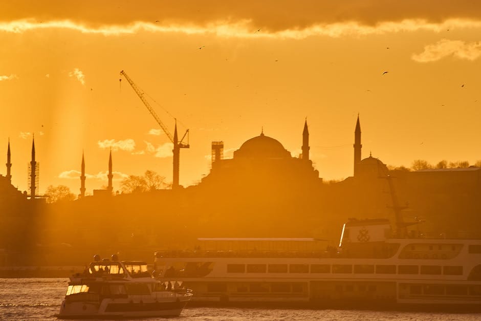 Silhouette of Istanbul skyline against a vibrant sunset with Bosphorus Ferries and iconic mosques.