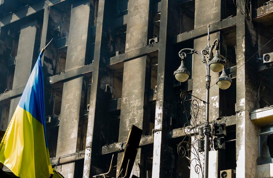 A damaged building in Kyiv, Ukraine with the Ukrainian flag displayed prominently.