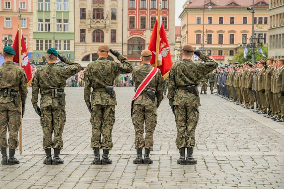 Polish soldiers saluting during a military parade in Wrocław city square, showcasing national pride.