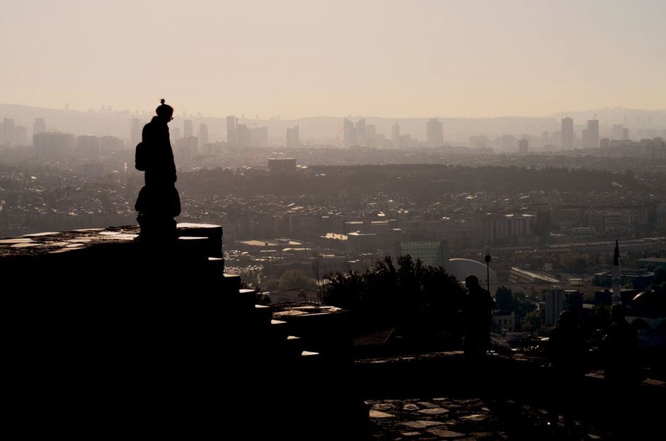 Silhouette of a person overlooking the Ankara skyline with a warm, moody sunset.