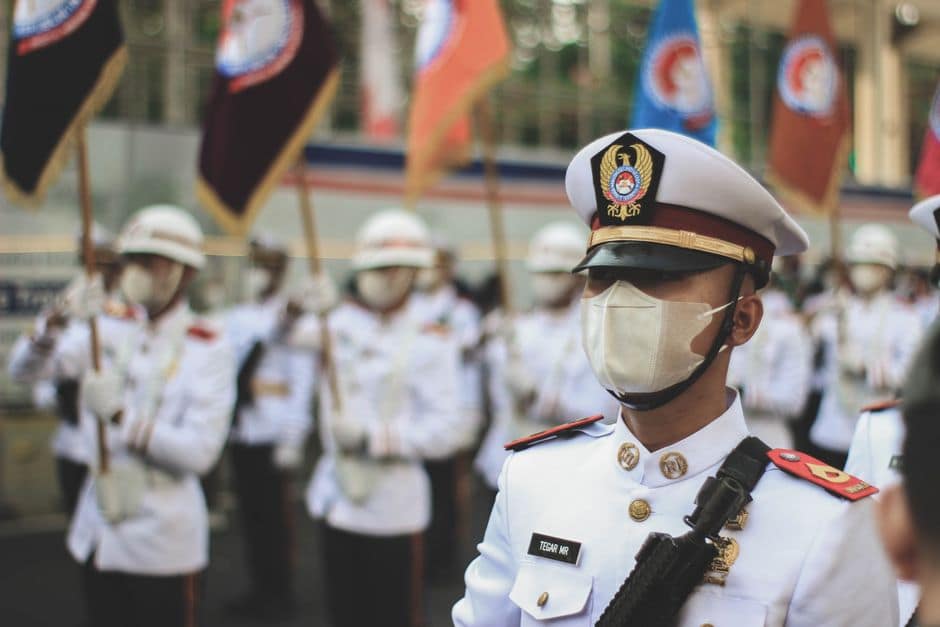 A group of soldiers in white uniforms wearing masks during a parade.