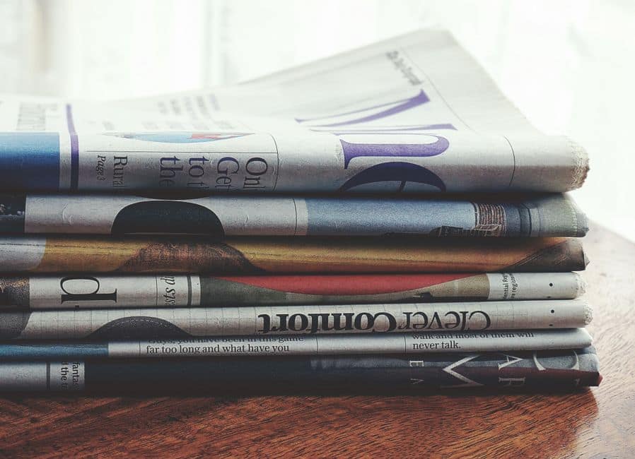 A stack of folded newspapers placed on a wooden table, symbolizing news and information.