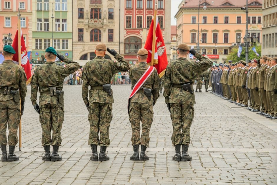 Polish soldiers saluting during a military parade in Wrocław city square, showcasing national pride.