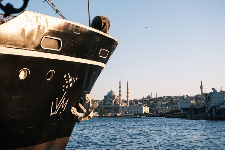 A large ship docked with the Istanbul skyline and mosques in the background during daylight.