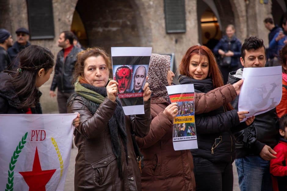 Group of protesters in Salzburg holding placards demanding peace with visible emotions.