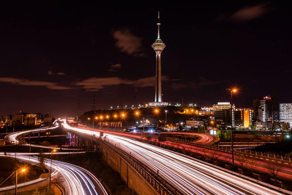 Stunning night view of Tehran's Milad Tower with light streaks from highway traffic.