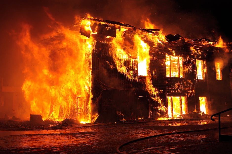 A dramatic nighttime scene of a house engulfed in flames in Tulan, Russia.