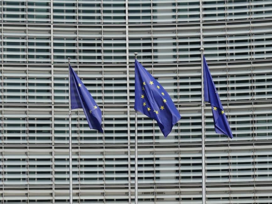 Three European Union flags waving outside the Berlaymont building in Brussels, Belgium.