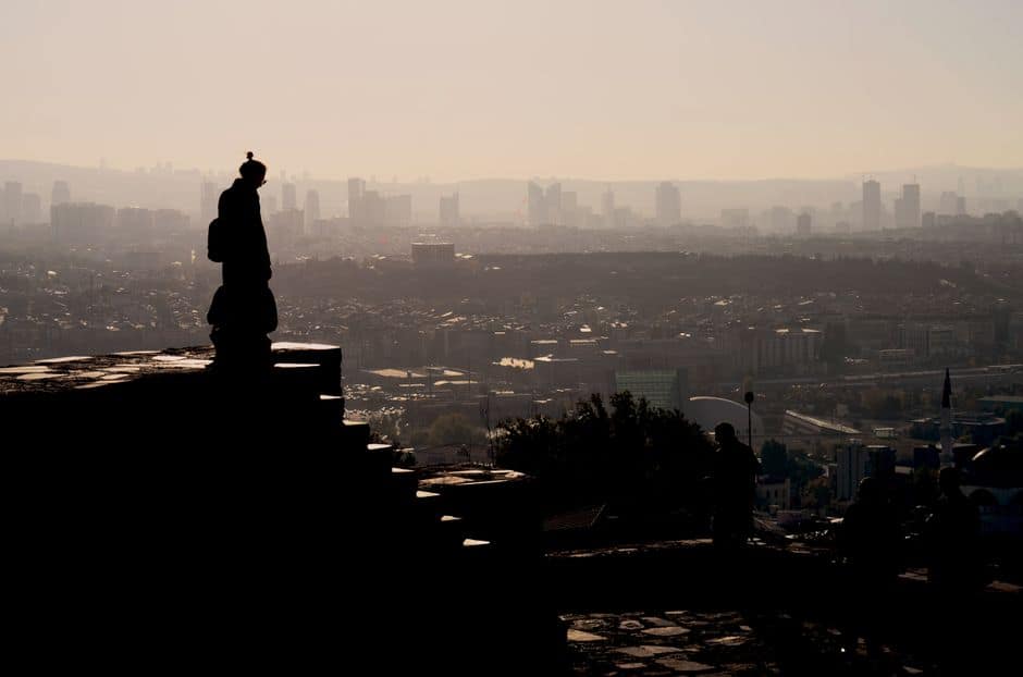 Silhouette of a person overlooking the Ankara skyline with a warm, moody sunset.