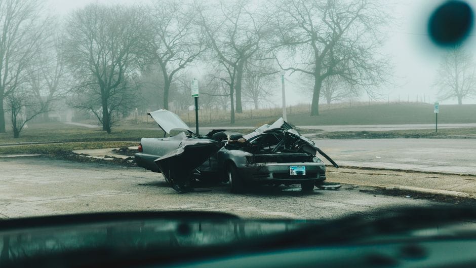 A foggy morning with a severely damaged car on a deserted street in Chicago.