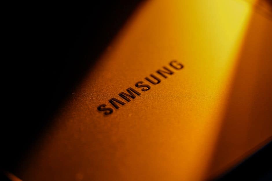 Dramatic close-up of a Samsung electronic device highlighted by golden lighting and shadows.