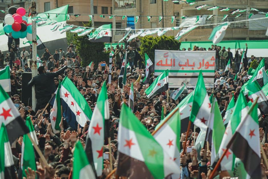 Syrian protest with flags and signs showcasing activism and unity in the streets.