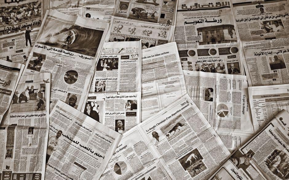 A variety of Arabic and French newspapers spread out, showcasing diverse articles and images.