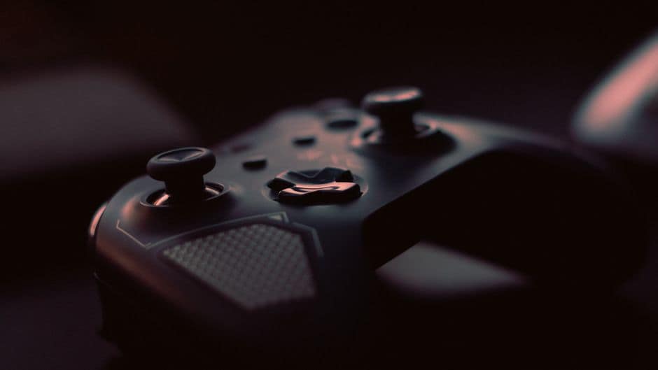 A close-up shot of a game controller in low light, highlighting its design and buttons.